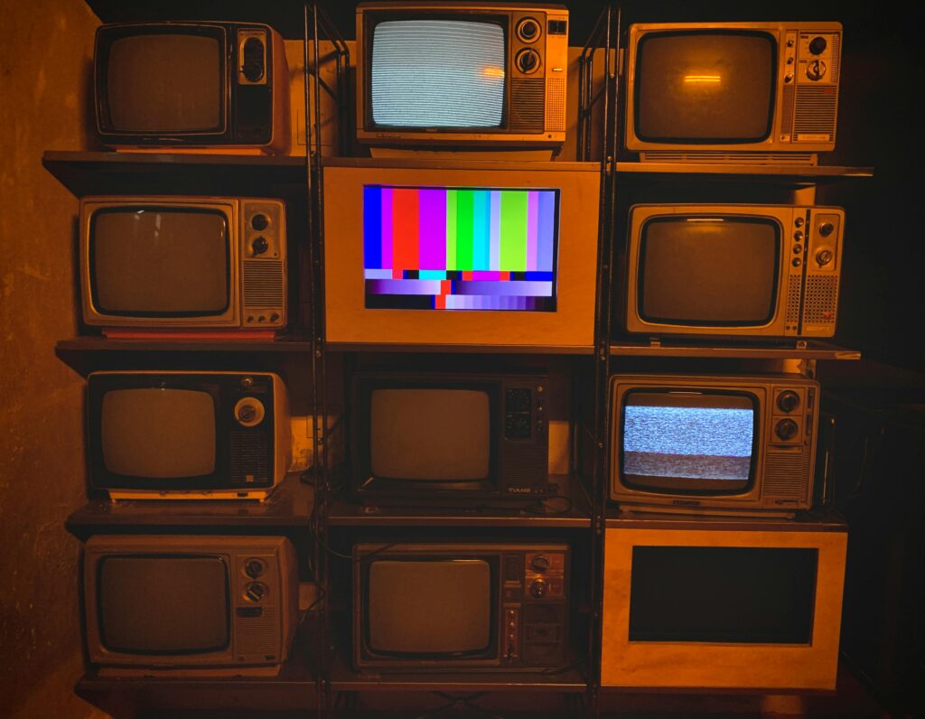 A collection of vintage televisions featuring static and color test patterns on the screens.